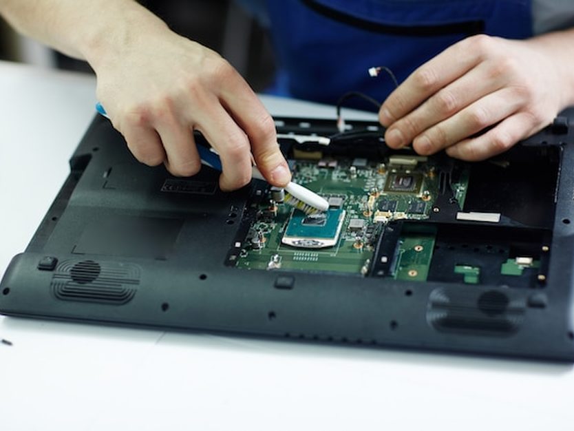 Técnico trocando a tela de um tablet sobre a bancada de reparos.